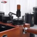 WDT-Tool und Dosierring auf einem Siebträger in einer Organizer-Box aus Holz, dahinter Distributoren und ein Kännchen
