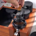 Hand dreht das WDT-Tool am Holzknauf, die Stifte stecken in einem Sieb mit Kaffeemehl