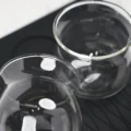 Zwei leere Sense-Gläser auf schwarzer Matte mit Wellenmuster, von oben durch die klaren Ränder gesehen