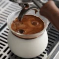 Nahe Draufsicht: Espresso wirbelt in die Milch in einem Sense-Glas auf der Abtropfschale