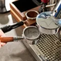 Siebträger mit dem Gewebe-Screen auf dem Kaffee, zur verchromten Brühgruppe einer Espressomaschine gehoben