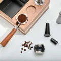 Siebträger mit Kaffeemehl im Loch des Organizers, Distributor, WDT-Tool und Bohnen auf dem weißen Tisch