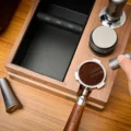 Draufsicht: Eine Hand zieht ein WDT-Tool durch den Kaffee in einem Siebträger im Loch des Organizers