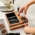 Hand setzt einen weißen Distributor in seine Aufnahme am Organizer, im Loch ein Siebträger mit Kaffee, dahinter eine Maschine