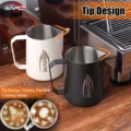 Beiges und schwarzes IKAPE V1 Kännchen unter einer Dampflanze, davor zwei Tassen mit Latte Art
