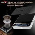 Silikonmatte über einer silbernen V2 Waage abgehoben, dahinter ein Pour-over-Dripper auf einer zweiten Waage