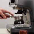 Siebträger mit Holzgriff auf dem schwarzen IKAPE Trichter auf der Tropfschale einer Espressomaschine