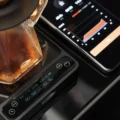 Schwarze IKAPE V2 Pro Waage unter einer Glaskaraffe, das Display zeigt Brühzeit, Verhältnis und Gewicht