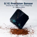 Schwarze V3 Waage hochkant in verstreutem Kaffeemehl, unter einer Überschrift zu ihrem Sensor mit 0,1 g