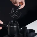 Hand hebt das V3 Tool von einem Siebträger mit Trichter, die feinen Nadeln hängen unter der Platte