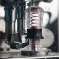 Tamper in Transparent Rot mit Wassertropfen, unter der Brühgruppe einer Espressomaschine