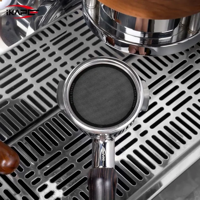 Schwarzes V4 Screen auf dem Kaffee in einem Siebträger, auf der Abtropfschale unter einer Brühgruppe