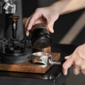 Hand hebt den V4 über einen Siebträger mit Kaffee und zeigt die konzentrischen Ringe der schwarzen Basis