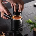 Zwei Hände senken den V5 auf einen Siebträger mit Kaffeemehl in einem schwarzen Siebträgerständer