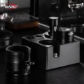 V6 Mini in einer schwarzen Tamperstation neben einem Distributor, vorne ein schwarzer Siebträgerhalter