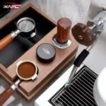 Draufsicht auf eine Organizer-Box aus Holz mit Tamper, Distributor und zwei Siebträgern neben einer Maschine