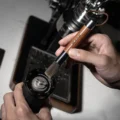 Hand kehrt mit der Bürste mit Nussbaumgriff den Mahlwerksbereich einer Mühle