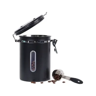 Höhere schwarze Dose offen auf Weiß, innen Bohnen, vorne ein gefüllter Löffel auf dem Tisch