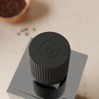 Single-Dose-Trichter von oben an einer Eureka Mignon in einer Küche, der Deckel mit dem Black-Tamp-Symbol