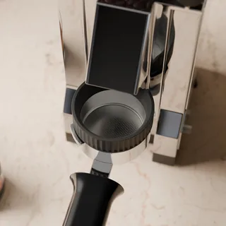 Dosiertrichter auf einem Sieb mit 58 mm von oben gesehen, unter dem Auswurf der Eureka Mignon in einer Küche