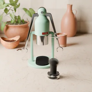 Schwarzer Tampergriff am Robot-Tamper vor einem Cafelat Robot in einer Küche