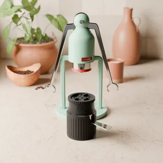 WDT-Tool auf dem Robot-Sieb im Siebträgerständer, vor einem mintfarbenen Cafelat Robot in einer Küche