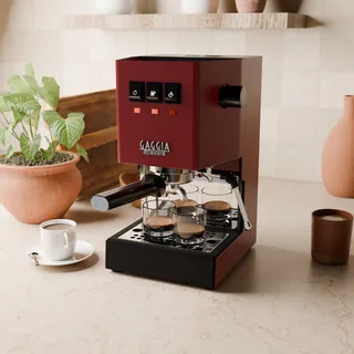 Weite Küchenansicht einer roten Gaggia Classic mit dem Wassertankspiegel, Pflanzen und Tassen ringsum