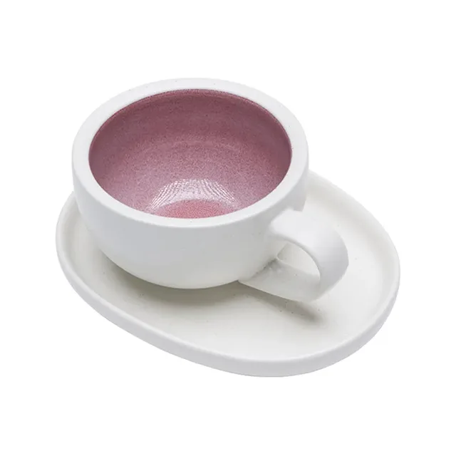Rosa Latte-Tasse und ovale Untertasse auf Weiß, innen gesprenkelte rosa Glasur, gebogener Henkel rechts
